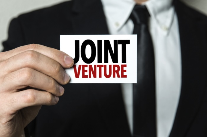 Businessman holding paper with 'joint venture' text