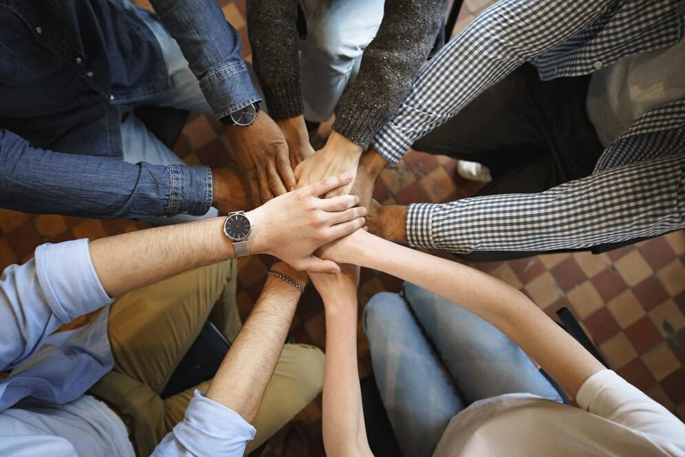 Group of people standing in a circle with hands stacked on top of each other